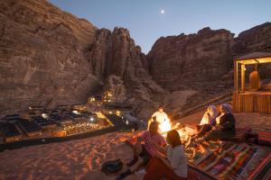 مخيم رحايب الصحراء في وادي رم: مجموعة من الناس يجلسون حول النار في الصحراء