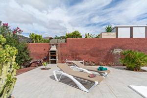 a patio with two lounge chairs and a brick wall at Villa Valentina Private Pool Playa Blanca By PVL in Playa Blanca