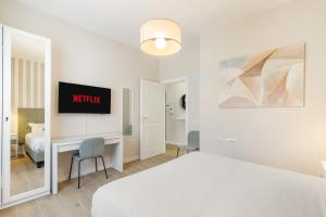 ein weißes Schlafzimmer mit einem Bett und einem Schreibtisch mit einem TV in der Unterkunft AlbaDea Apartment in Rom
