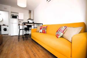 een woonkamer met een gele bank met kussens erop bij Blue Sand Apartment in Costa Teguise in Costa Teguise
