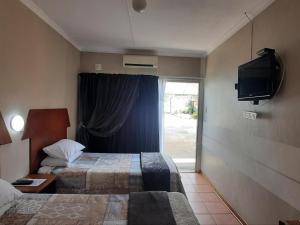 una camera d'albergo con due letti e una televisione di Kalahari Kaja a Kuruman