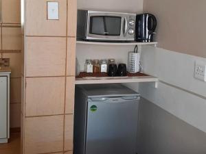 a small kitchen with a microwave and a small refrigerator at Kalahari Kaja in Kuruman