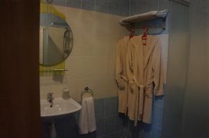 a bathroom with a sink and a robe on a rack at Guest House Golden Flake 4km from Bolata beach in Bŭlgarevo