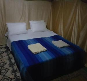 a bed with two pillows and two towels on it at Merzouga nomad style in Merzouga