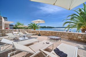 a patio with chairs and an umbrella and the water at Livingstone Beach House in Trogir
