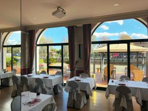 a restaurant with white tables and chairs and large windows at Hotel Bentivoglio Residenza D'Epoca in Bentivoglio
