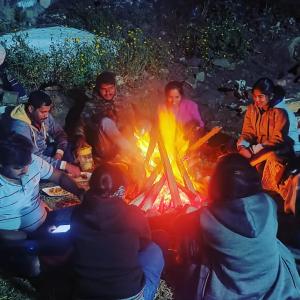 um grupo de pessoas sentadas à volta de uma fogueira em Sugan Residency em Kodaikanal