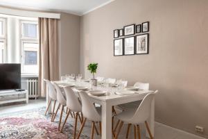 una sala da pranzo bianca con tavolo e sedie bianchi di 2ndhomes Bright & Spacious, 5 Bedroom Apartment in the Center a Helsinki