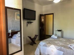um quarto com uma cama e uma televisão na parede em Pousada Recanto de Praia Seca em Araruama