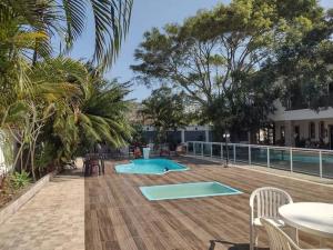 dwa baseny ze stołami, krzesłami i drzewami w obiekcie Pousada Recanto de Praia Seca w mieście Araruama