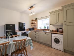 a kitchen with a table and a sink and a dishwasher at Charlotte's Cottage in Seahouses