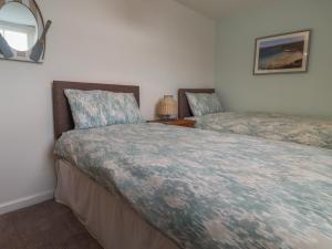 a bedroom with two beds and a mirror at Charlotte's Cottage in Seahouses