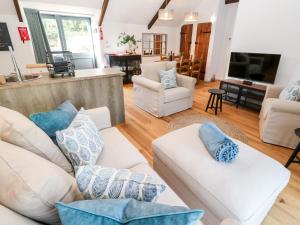 a living room with white couches and blue pillows at Carines Barns - Pol in Newquay