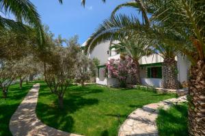 ein Garten mit Palmen und ein Haus in der Unterkunft Studios Vrettos Beachside Hotel in Plaka