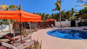 une piscine avec parasols et chaises et une piscine dans l'établissement Pufferfish Villas, à Loreto