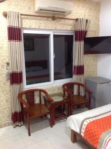 a bedroom with a window and two chairs and a bed at Ngoc Binh Hotel in Hue