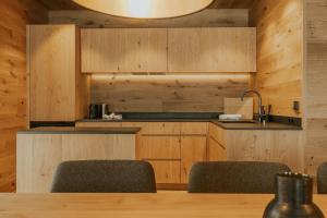 uma cozinha com armários de madeira e uma mesa com cadeiras em Boutique Chalet Almrausch em Lech am Arlberg