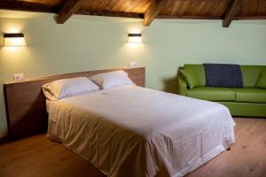 1 dormitorio con 1 cama y 1 sofá verde en Pallozas Turisticas Ridicodias - A Pedra, 