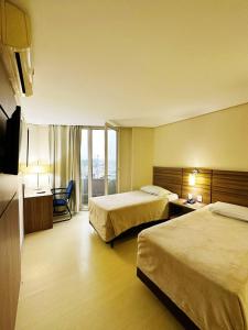 a hotel room with two beds and a balcony at Umbu Hotel Porto Alegre - Centro Histórico - Prox Aeroporto 15min in Porto Alegre