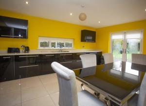 une cuisine avec des murs jaunes, une table et des chaises dans l'établissement Rosslare Strand Holiday Home, à Rosslare