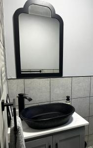 baño con lavabo negro y espejo en Palm Tree Cottage Felixton en Richards Bay