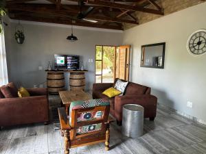 a living room with couches and a table at Palm Tree Cottage Felixton in Richards Bay