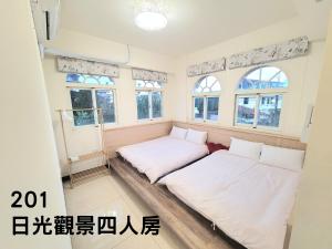 two beds in a room with windows at Zhen Mei Lu Villa in Puli