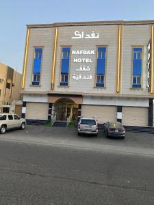 two cars parked in a parking lot in front of a hotel at نفداك للشقق الفندقية المفروشة in Khamis Mushayt