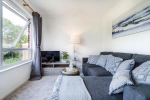 a living room with a gray couch and a window at Longbridge Apartment- 1BR Close to Gatwick in Hookwood