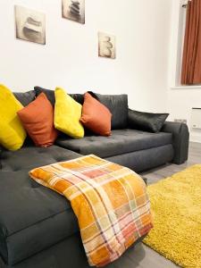 - un canapé noir avec des oreillers colorés dans le salon dans l'établissement Leicester City Centre Apartment with Parking, à Leicester