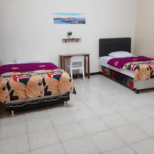een slaapkamer met 2 bedden en een tafel en een stoel bij Dannu's Homestay Ijen and Bromo Tour in Banyuwangi