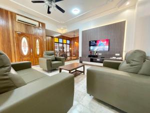 Il comprend un salon avec des canapés et une télévision à écran plat. dans l'établissement Langkawi Cozy Holiday Home at Bukit Indah by Zervin, à Kuah