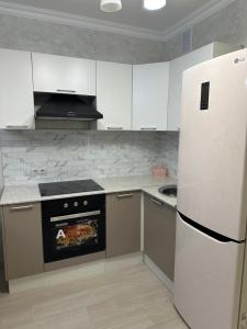 cocina con electrodomésticos blancos y nevera blanca en однокомнатная квартира en Prigorodnyy