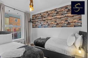 a bedroom with a bed and a brick wall at LUXE 3 BED - Central Reading - Free Parking in Reading