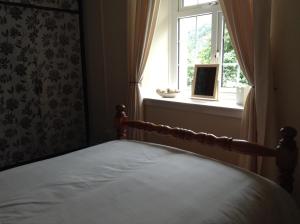 a bed in a bedroom with a window and a bed frame at Darroch View Cottage in Invermoriston