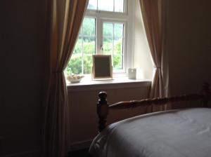 a bedroom with a bed and a window with a book at Darroch View Cottage in Invermoriston