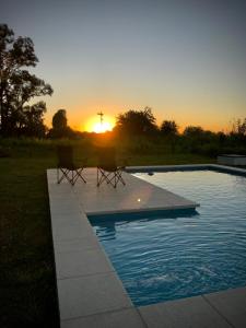 Duas cadeiras sentadas ao lado de uma piscina ao pôr-do-sol em postodivino em Ruiz