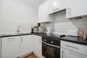 eine Küche mit weißen Schränken und einer schwarzen Arbeitsplatte in der Unterkunft (G2) Central 1 Bed Blythswood Flat in Glasgow