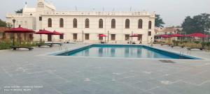 a swimming pool in front of a white building at BUDDHA HERITAGE RESORT in Bodh Gaya