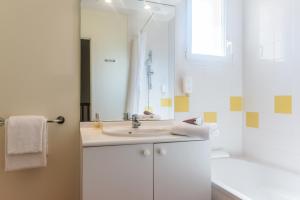 a white bathroom with a sink and a mirror at Zenitude Hôtel-Résidences Nantes - La Beaujoire in Nantes