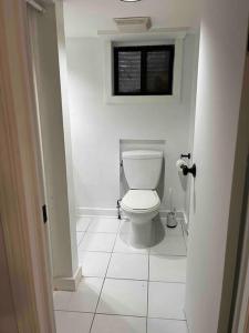 a white bathroom with a toilet in a room at Downtown Basement Suite in Toronto