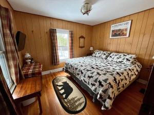 1 dormitorio con 1 cama en una habitación con paredes de madera en Moose Riverside Bungalow 3BR Home Old Forge NY, en Old Forge
