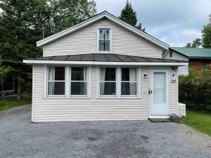 una pequeña casa blanca con una puerta blanca en Moose Riverside Bungalow 3BR Home Old Forge NY, en Old Forge