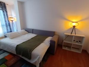 a bedroom with a bed and a nightstand with two lamps at Acogedora Vivienda de 2 Habitaciones y Terraza in Vimianzo