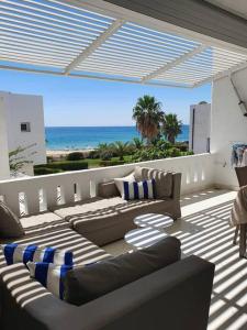 a patio with couches and the ocean in the background at bel appartement vue sur mer in Nabeul