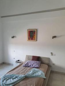 a bed in a white room with a picture on the wall at bel appartement vue sur mer in Nabeul