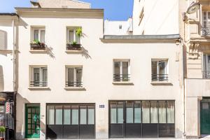 eine Fassade eines weißen Gebäudes mit Fenstern in der Unterkunft Rome Batignolles - Luxe Charme - 2P in Paris