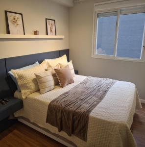um quarto com uma cama com almofadas e uma janela em Living For Consolação em São Paulo
