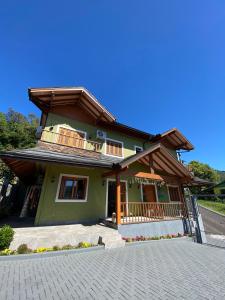 Casa verde con balcón y entrada en Apartamento Petri, en Gramado