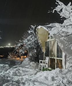 a snow covered house with a chair in front of it at Waterfall valley stay in Palchān